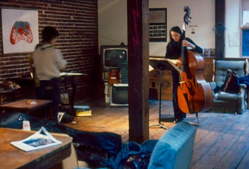 Artist Judy Rifka (left) prepares for her exhibition while French contrabassist Joelle Leandre (right) practices at Hallwalls, 1977.